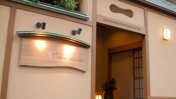 Fachada de edificio con placa, planta en maceta y una lámpara.