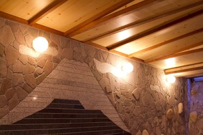 A staircase with stone walls and wooden beams, illuminated by round lights. - Yugawara Retreat Goen no Mori (Yugawara)