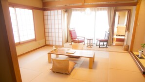 Una habitación japonesa tradicional con suelo de tatami, una mesa de madera baja y dos sillas.