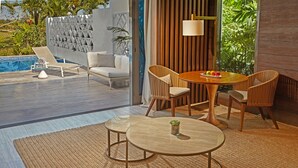 Un área de estar moderna al aire libre con piscina, sillones reclinables y una mesa de comedor con sillas.