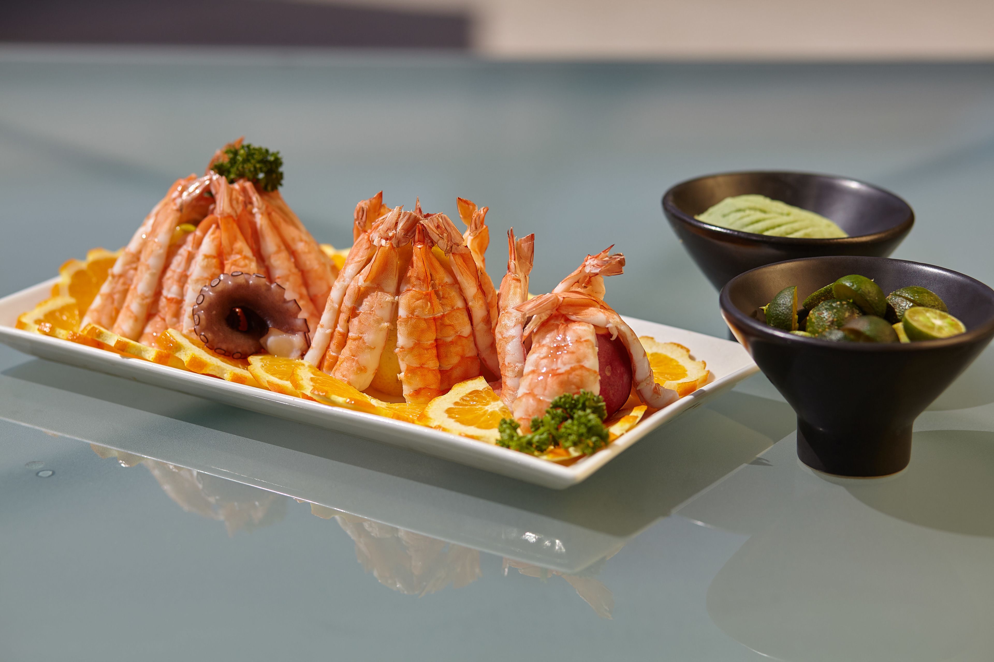 A plate of shrimp and a bowl of green sauce.