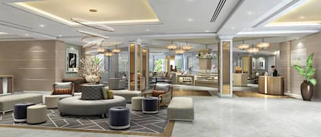 A modern hotel lobby with a central seating area, a reception desk, and a view of the kitchen area.