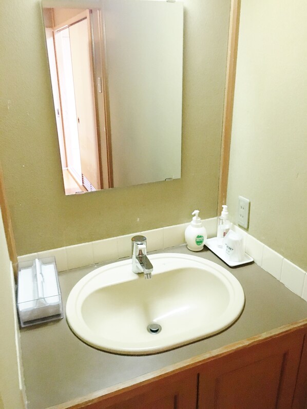 A bathroom with a sink, mirror, and toiletries. - Yumoto Hounoya (Yoshino)