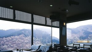 Habitación amplia con un gran ventanal con vistas a un paisaje montañoso. Cuenta con un sofá, una mesa de centro y varias sillas dispuestas para sentarse.