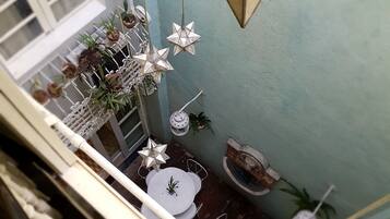 A balcony with a white railing, a star-shaped hanging light, potted plants, and a small table with chairs.