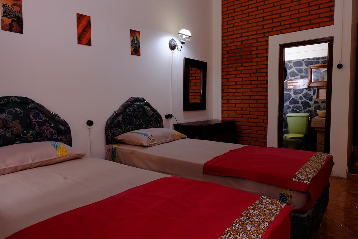 A hotel room with two beds, a brick wall, and a mirror.