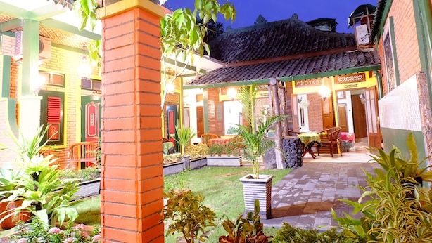 A courtyard with a tiled floor, potted plants, and a brick pillar. - Kampoeng Djawa Guesthouse (Yogyakarta)