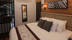 A bedroom with a large bed, a wooden headboard, a mirror, and a wall-mounted artwork. - Reunion Heritage House (George Town)