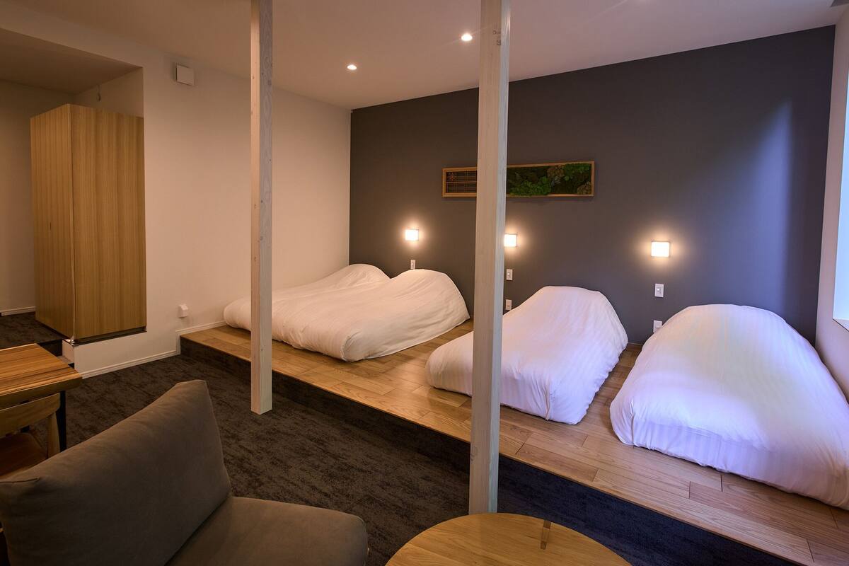 A hotel room with a bed, a wooden desk, a chair, and a small table.