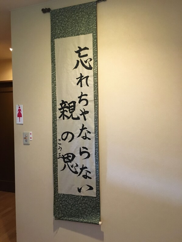 Un cartel vertical con texto en japonés sobre una pared.