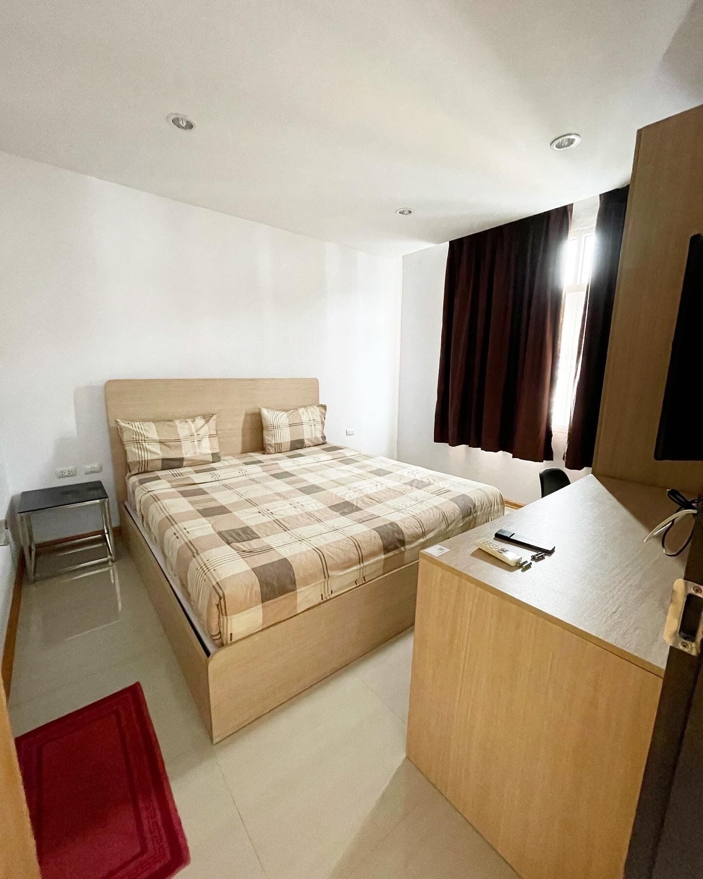 Una habitación de hotel con cama, mesita de noche, escritorio y espejo.