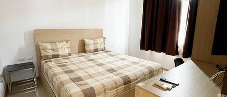 Una habitación de hotel con cama, mesita de noche, escritorio y espejo.