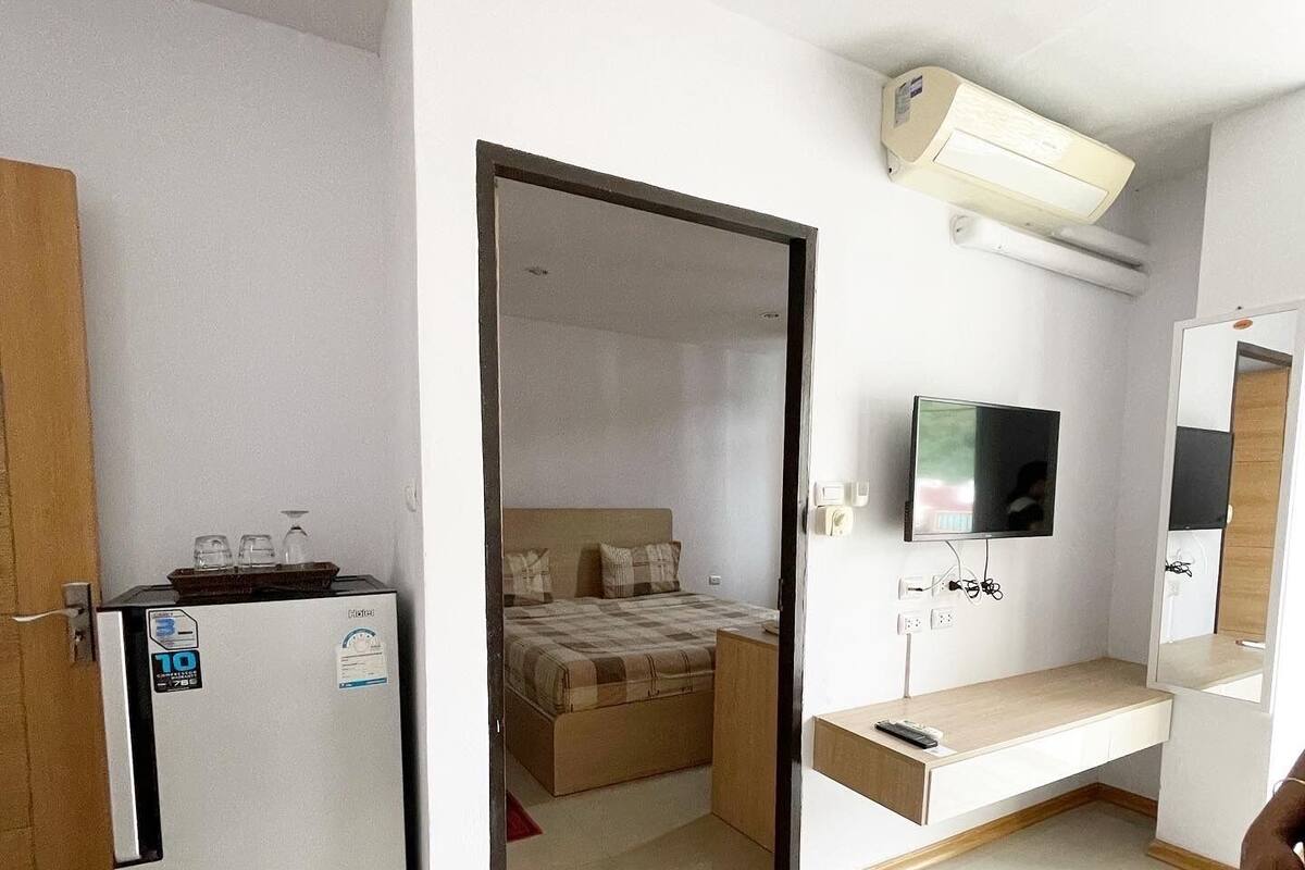 Habitación de hotel pequeña con kitchenette, una cama con cabecera, televisor montado en la pared y una zona de estar.