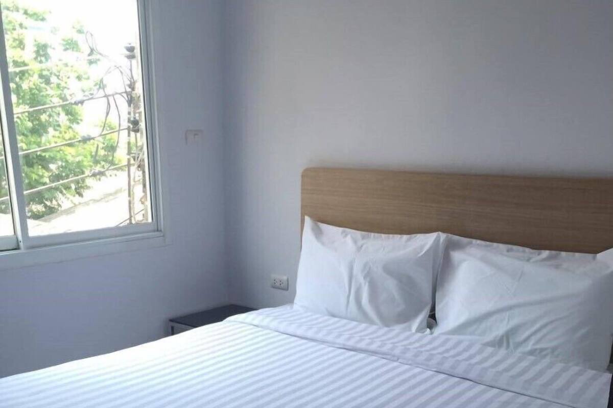 Una cama bien hecha con sábanas blancas en una habitación con ventana.