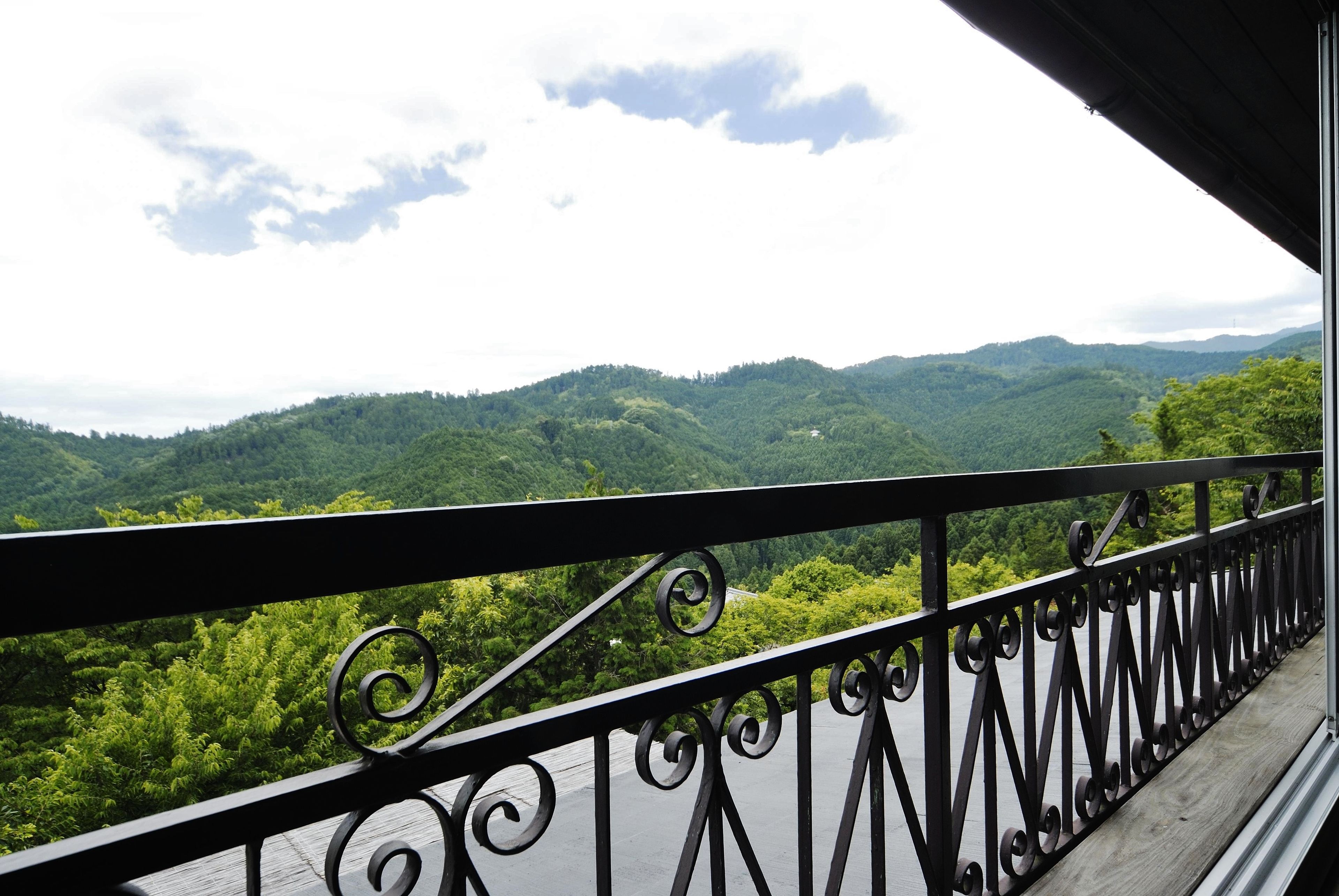 A balcony with a wrought iron railing overlooking a mountainous landscape.