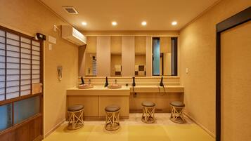 A hotel bathroom with a sink, mirror, and three stools.