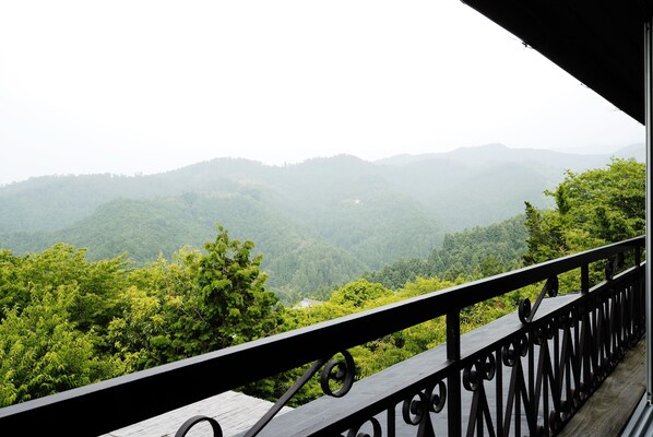 A balcony with a view of a forested mountain range.