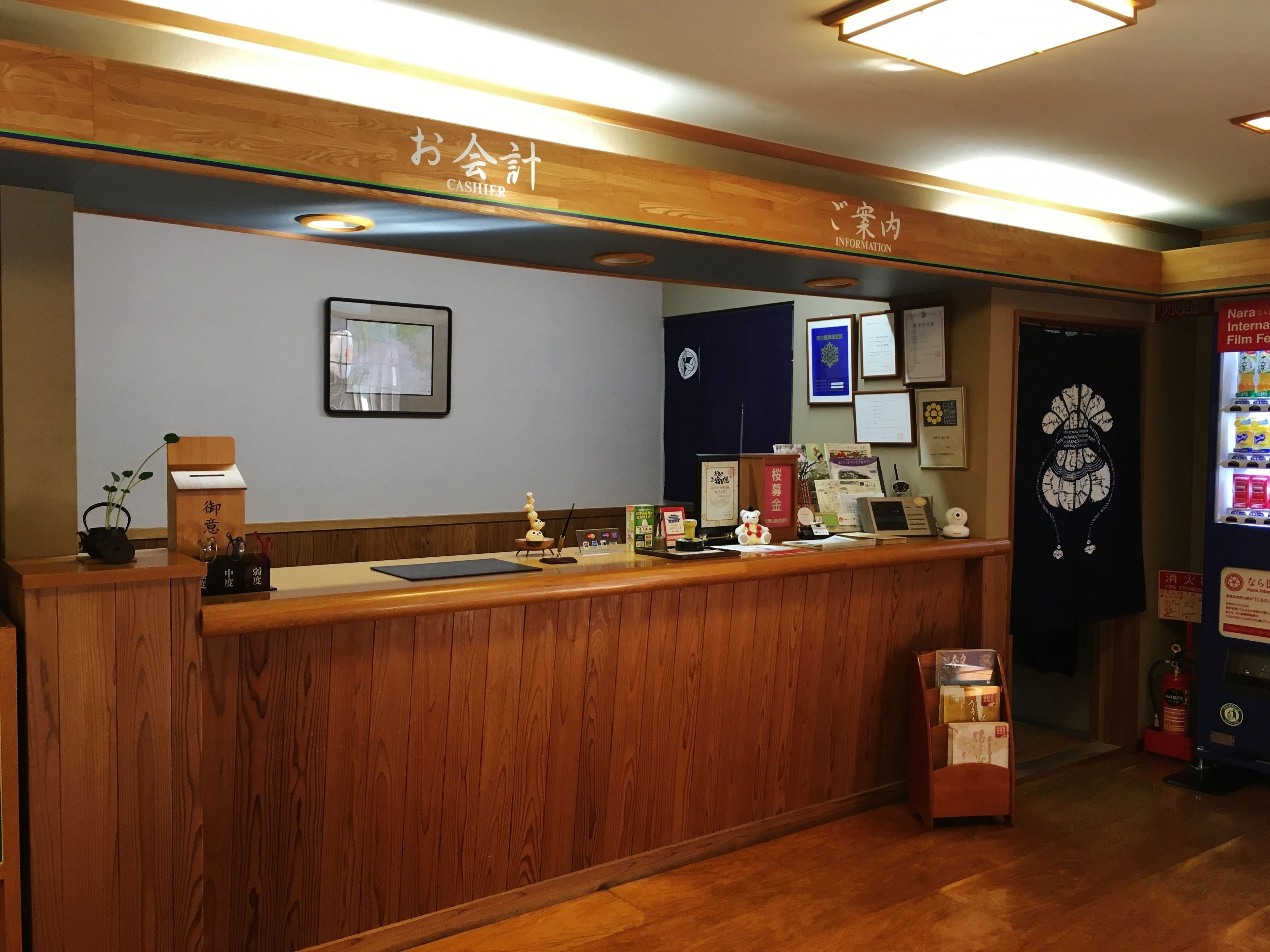 A wooden reception desk with a cash register, framed certificates, and a small plant.