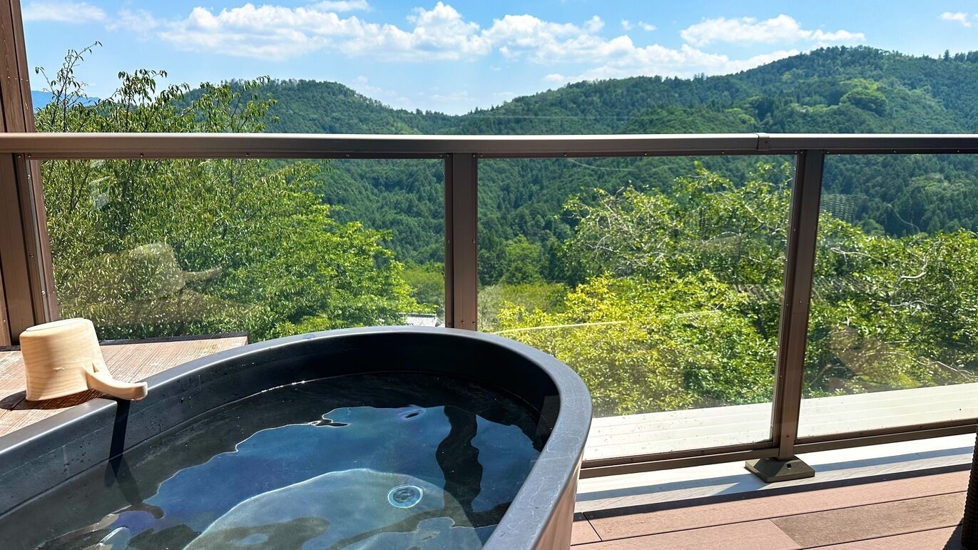 A hot tub on a balcony with a view of a forested mountain.
