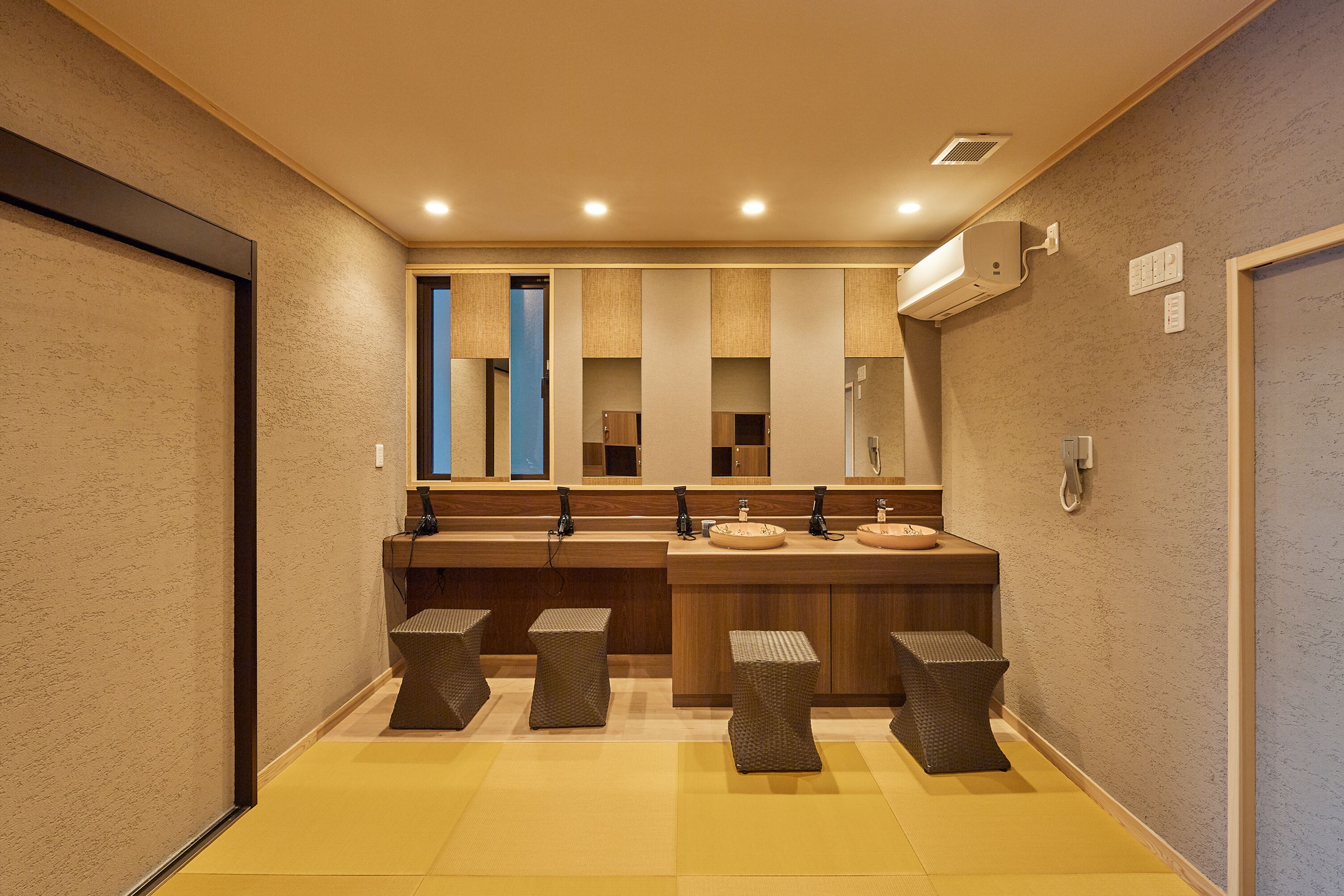 A modern bathroom with a central sink, two mirrors, and a wall-mounted air conditioner.