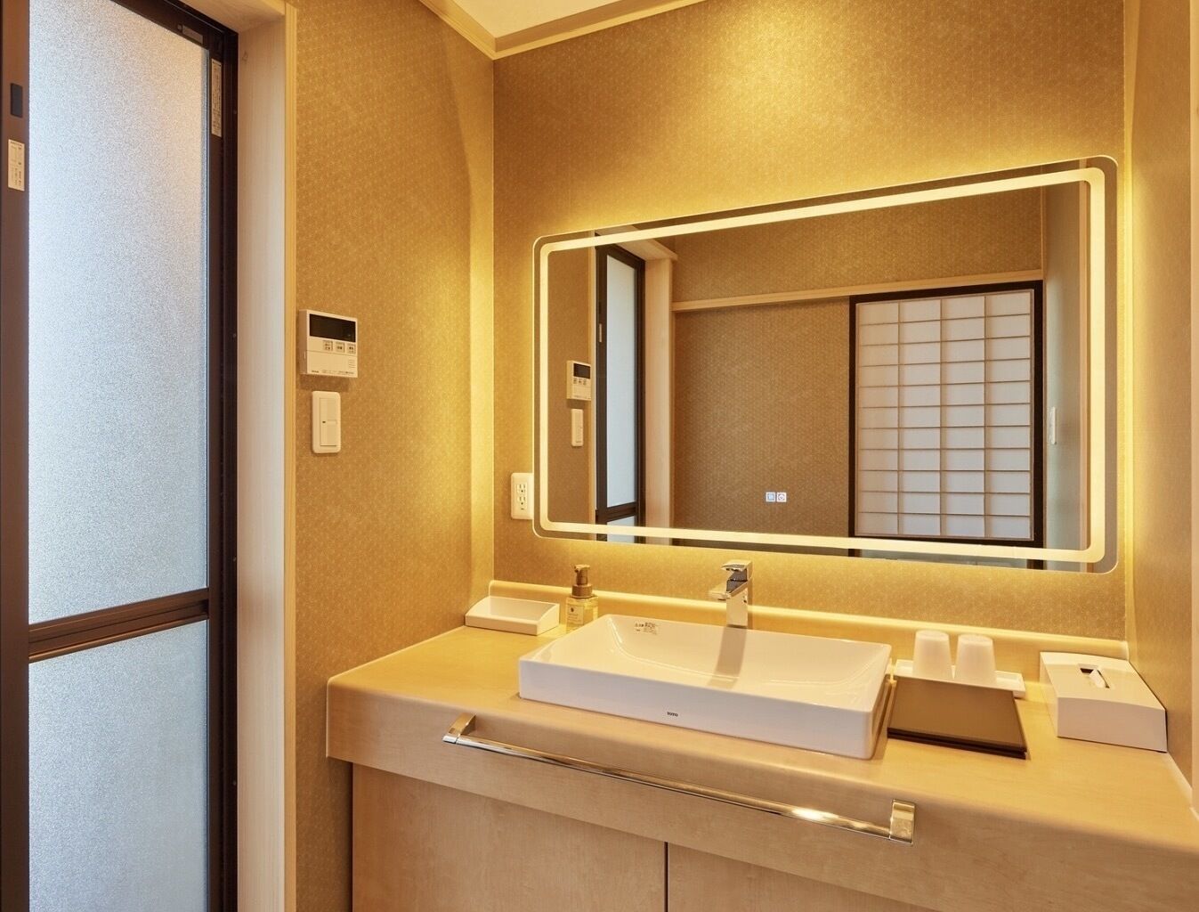 A modern bathroom with a large mirror, a sink, and a towel rack.