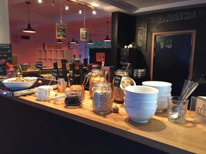 A breakfast bar with various food items and condiments, including jars of granola and yogurt, and a coffee menu on the wall. - Fugl Fønix Hotel (Etne)