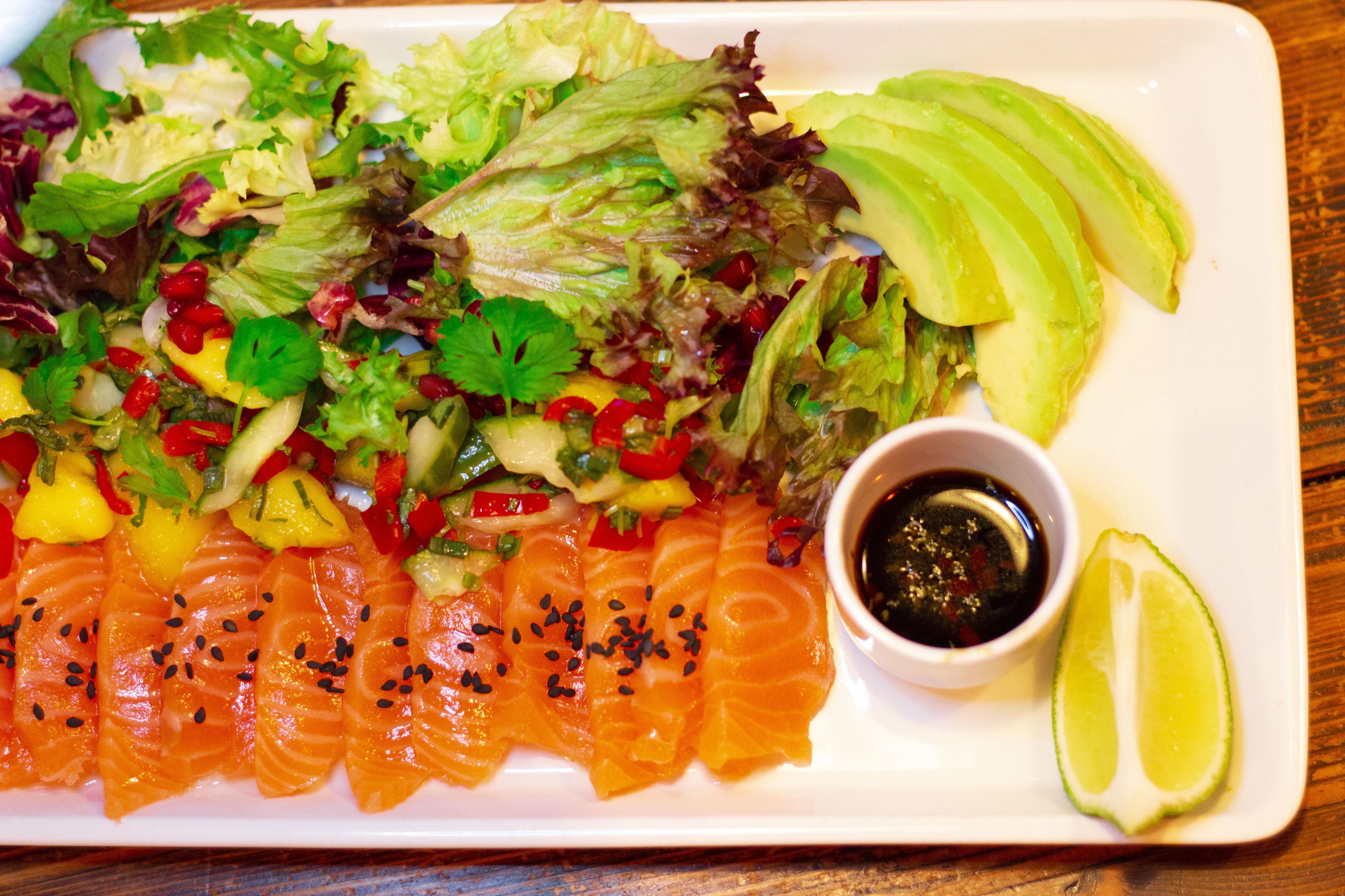 A plate of sushi with avocado and a side salad.