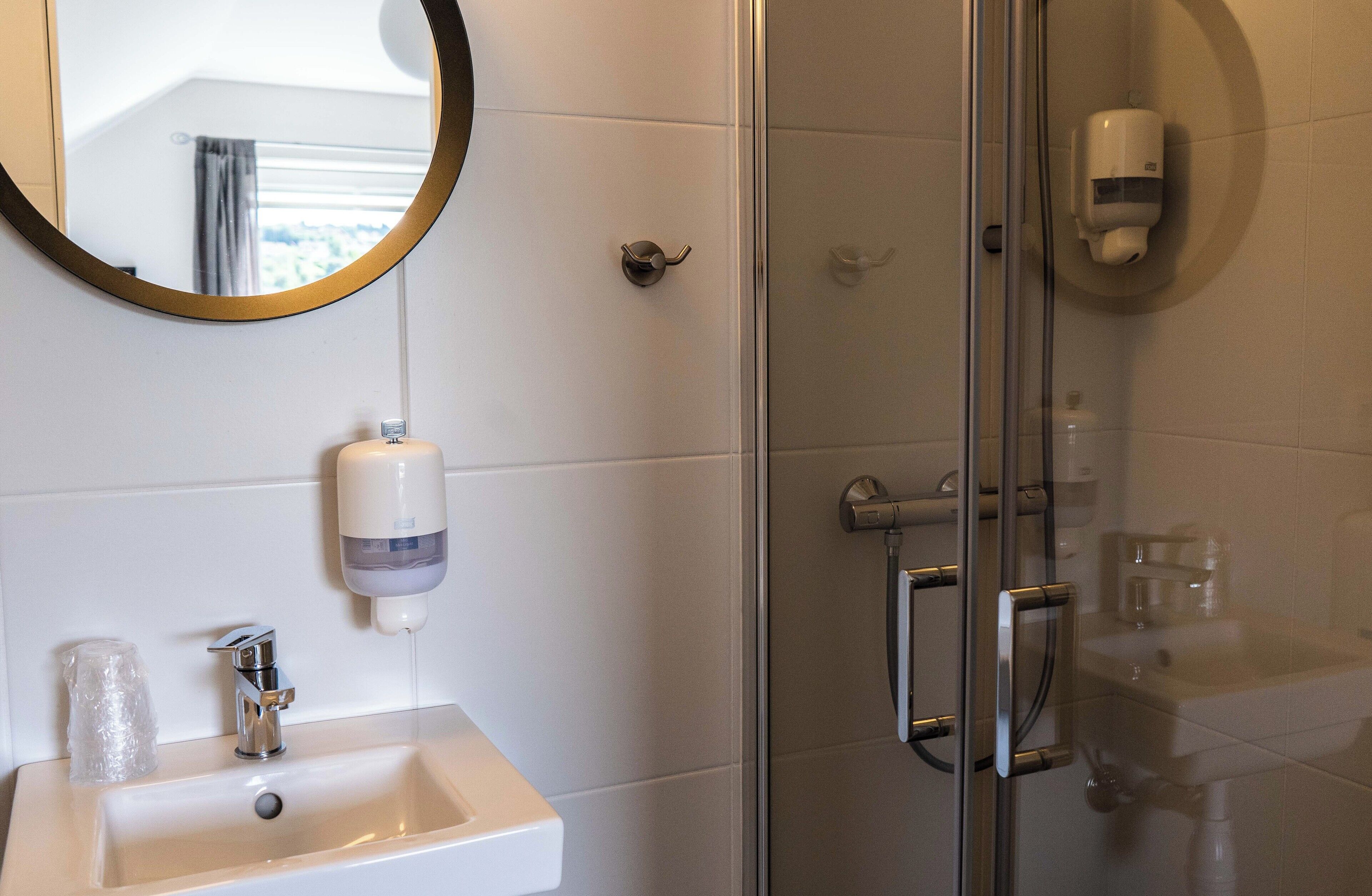 Ein Badezimmer mit Waschbecken, Spiegel und Duschkabine aus Glas.
