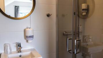 Ein Badezimmer mit Waschbecken, Spiegel und Duschkabine aus Glas.
