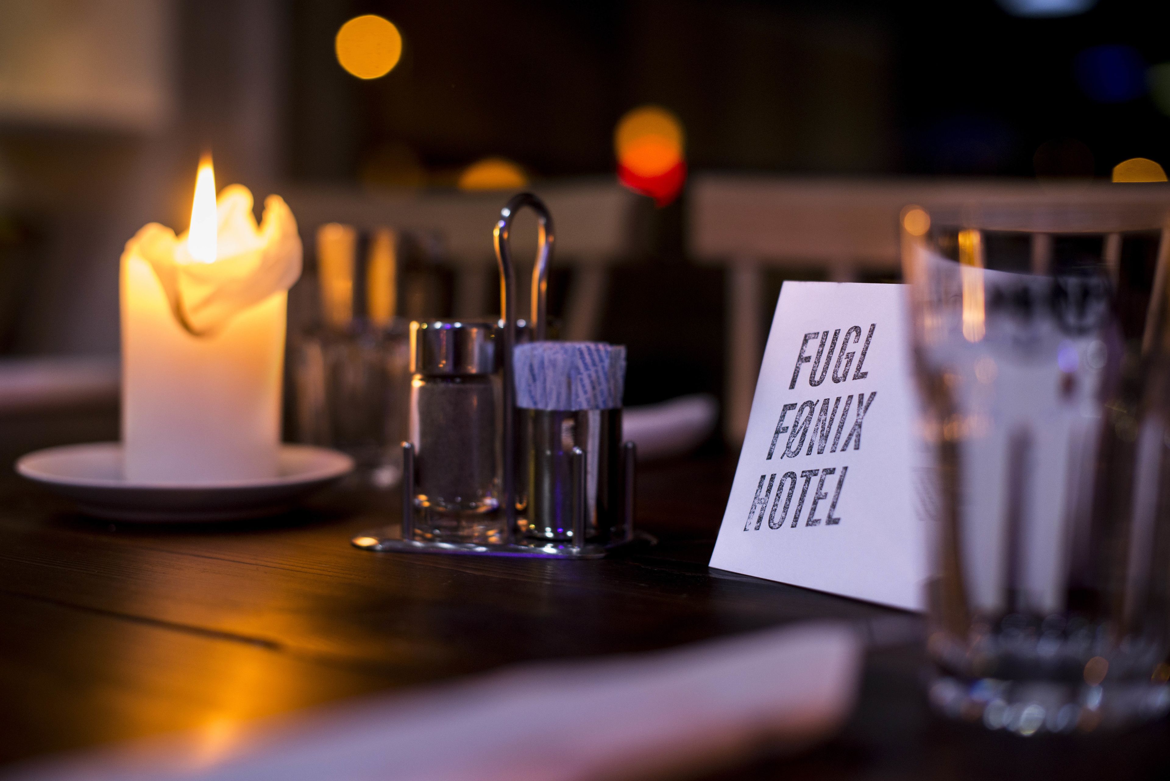 Una vela, un vaso y un letrero que dice "Fugl Frank Hotel".