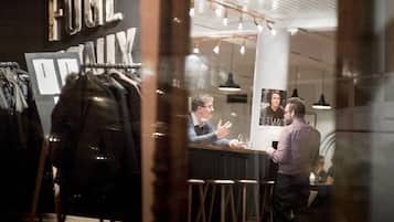 A bar area with stools and a counter, a clothing rack with jackets, and a sign that reads "FUGL FAMILY".