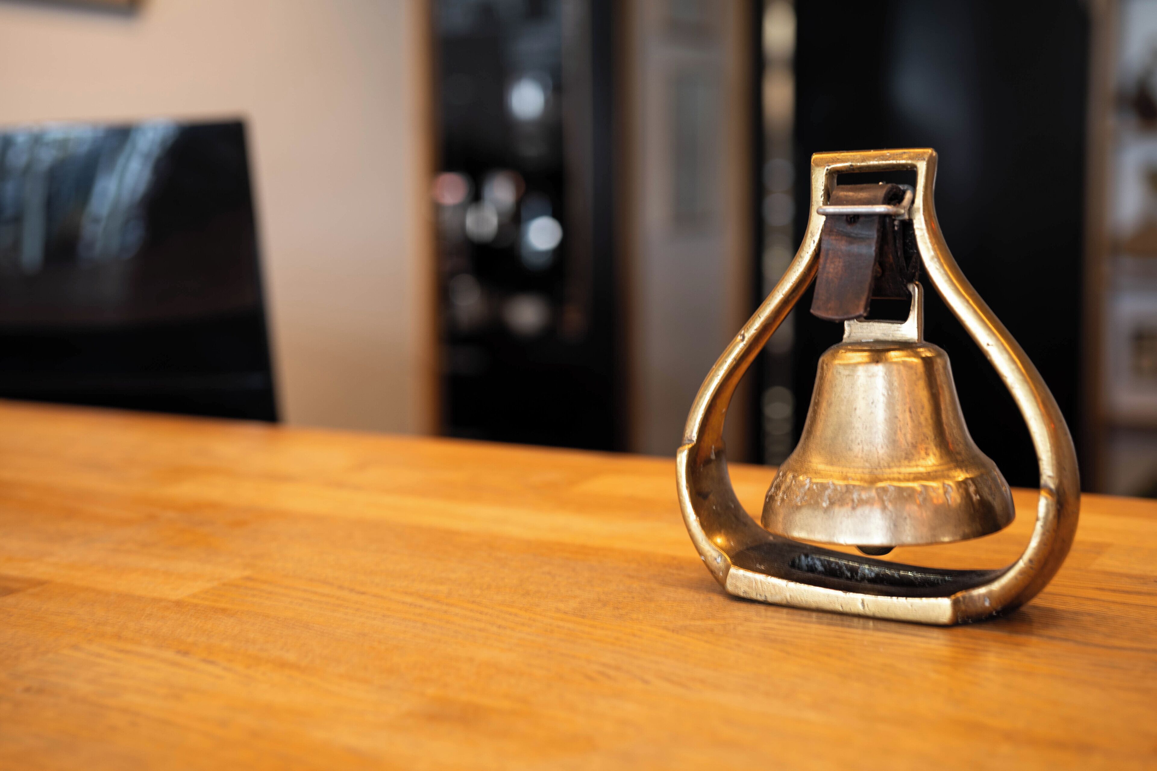 A brass bell-shaped object on a wooden surface.