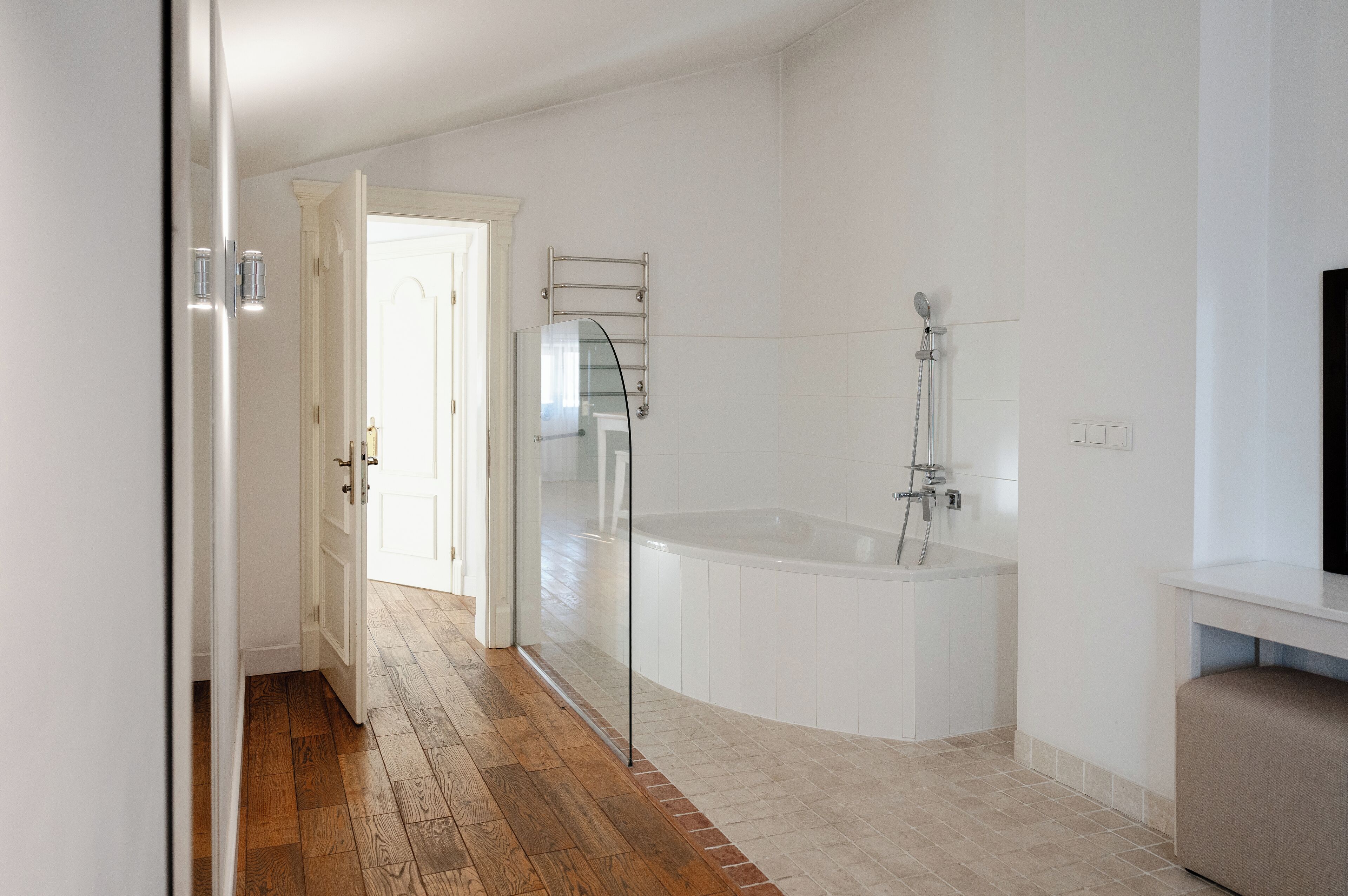 Un baño moderno con cabina de ducha de vidrio, una bañera independiente y suelo de madera.