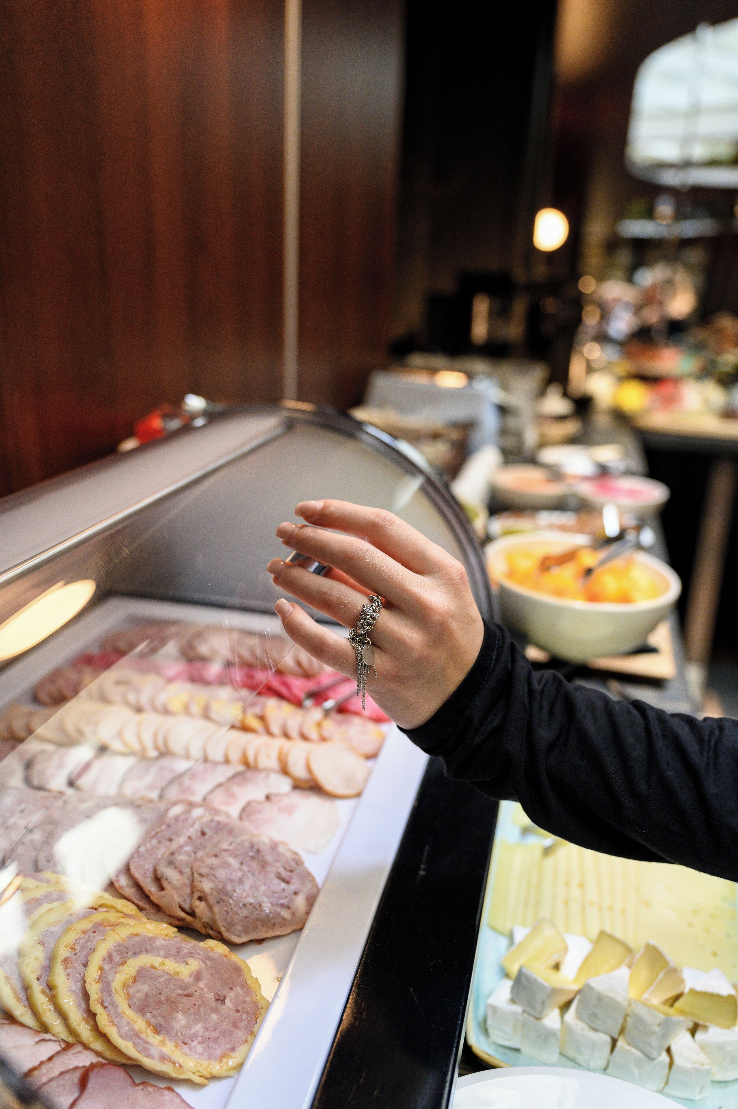 A buffet with various food items including sliced meats, cheeses, and pastries.