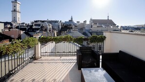 A rooftop terrace with a view of a cityscape, including a clock tower and various buildings. - Rudolfo  Hotel (Lviv)