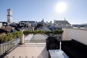 A rooftop terrace with a view of a cityscape, including a clock tower and various buildings.