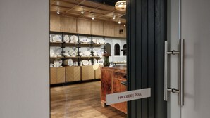 A store interior with wooden shelves displaying ceramic items. A sign reads "HA CESE | PULL".
