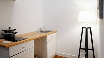 A compact kitchen with a wooden countertop, a sink, and a stove.