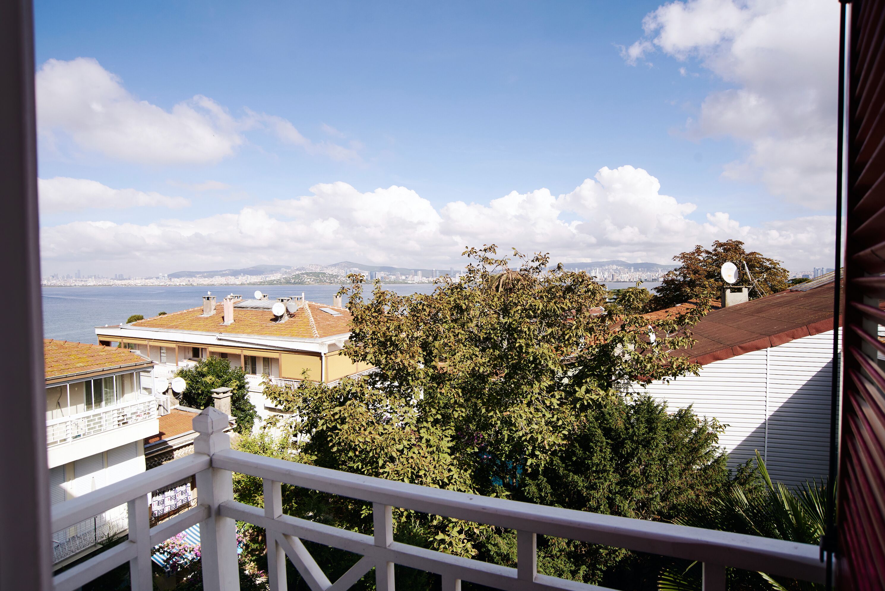 A balcony with a view of a cityscape, including buildings and a body of water.