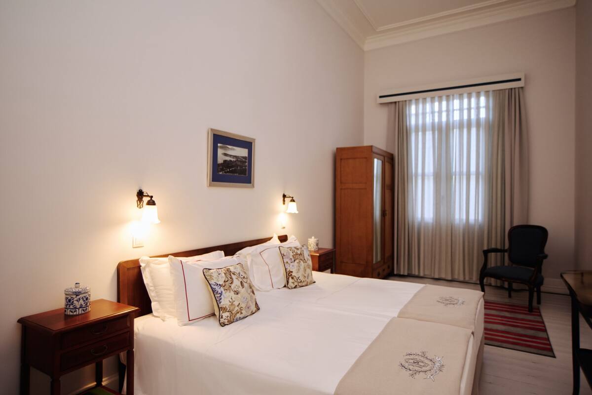Une chambre d’hôtel avec un grand lit, des tables de chevet, une armoire et une chaise.