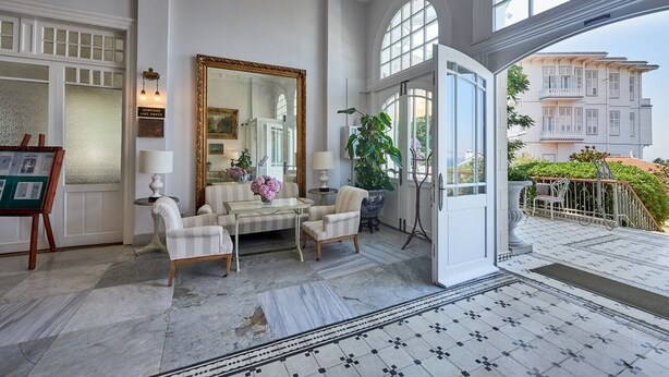 Una habitación amplia con un espejo grande, un conjunto de sofás y una planta en maceta.