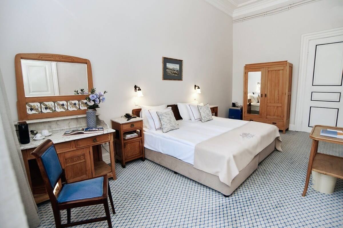 Une chambre d’hôtel comprenant un lit, un bureau, une chaise, une armoire et un miroir.