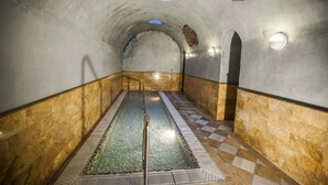A tunnel-like interior with a checkered floor, a central water feature, and stone walls. - Hotel Balneario de Graena (Cortes y Graena)