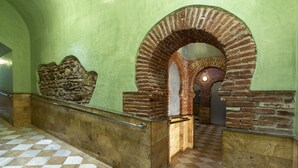 A hallway with a checkered floor, a stone wall, and a brick archway. - Hotel Balneario de Graena (Cortes y Graena)