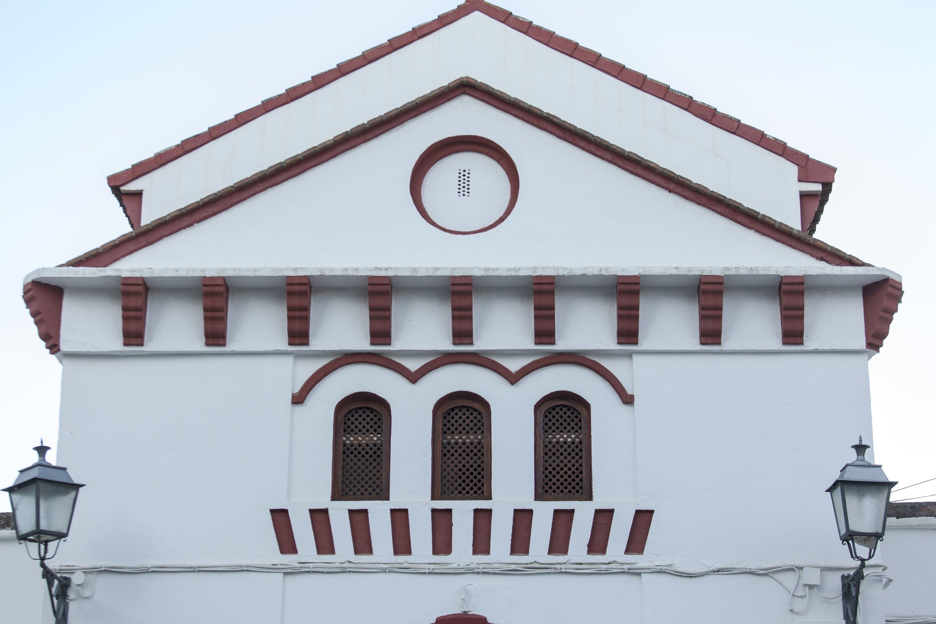 Un edificio blanco con techo rojo y tres ventanas arqueadas.