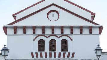 Un edificio blanco con techo rojo y tres ventanas arqueadas.