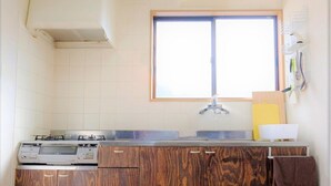 A kitchen with a built-in stove, a window above the sink, and a towel hanging on the right. - Yoshimura (Fujikawaguchiko)