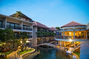 Un hotel con varios pisos, piscina al aire libre y zona de restaurante.