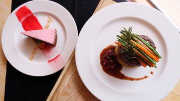 Two white plates with food on a wooden board.