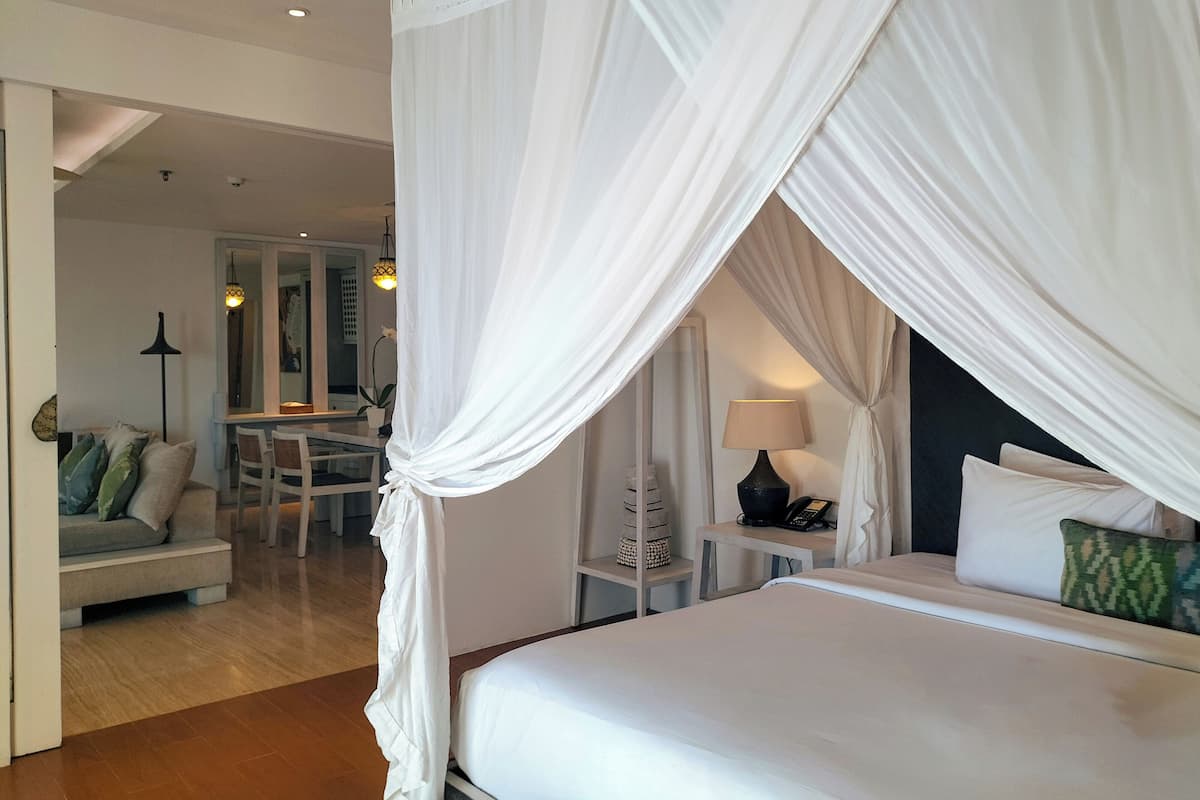 A hotel room with a bed, a desk, a chair, a lamp, and a nightstand.